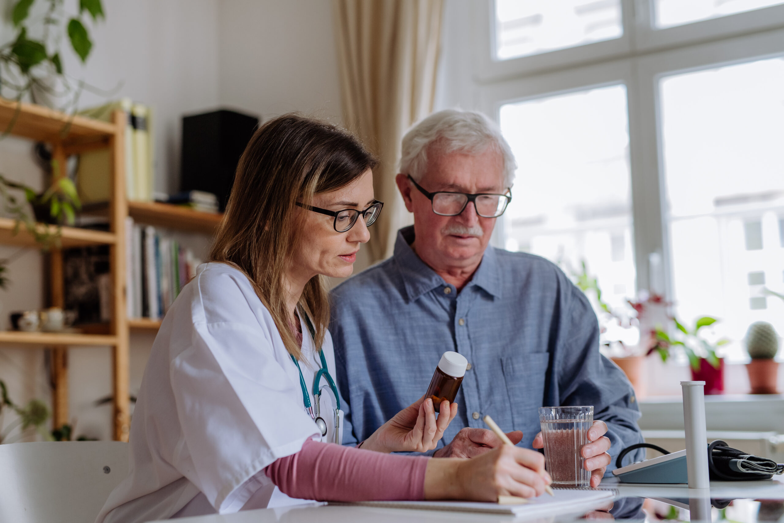 Healthcare worker and senior man reviewing medication at home