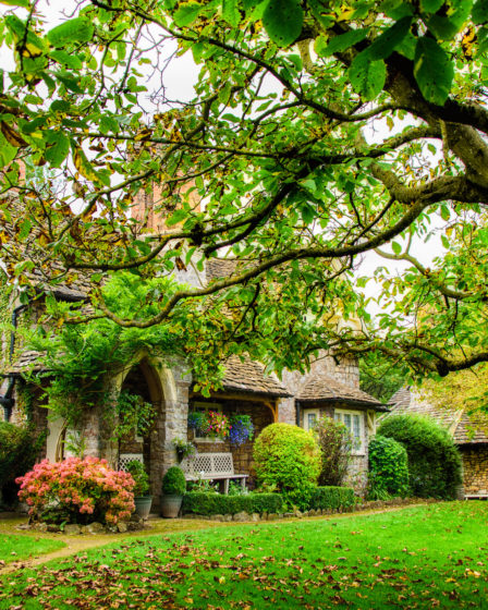 Quaint English cottage in autumn foliage and garden, evoking character and charm.