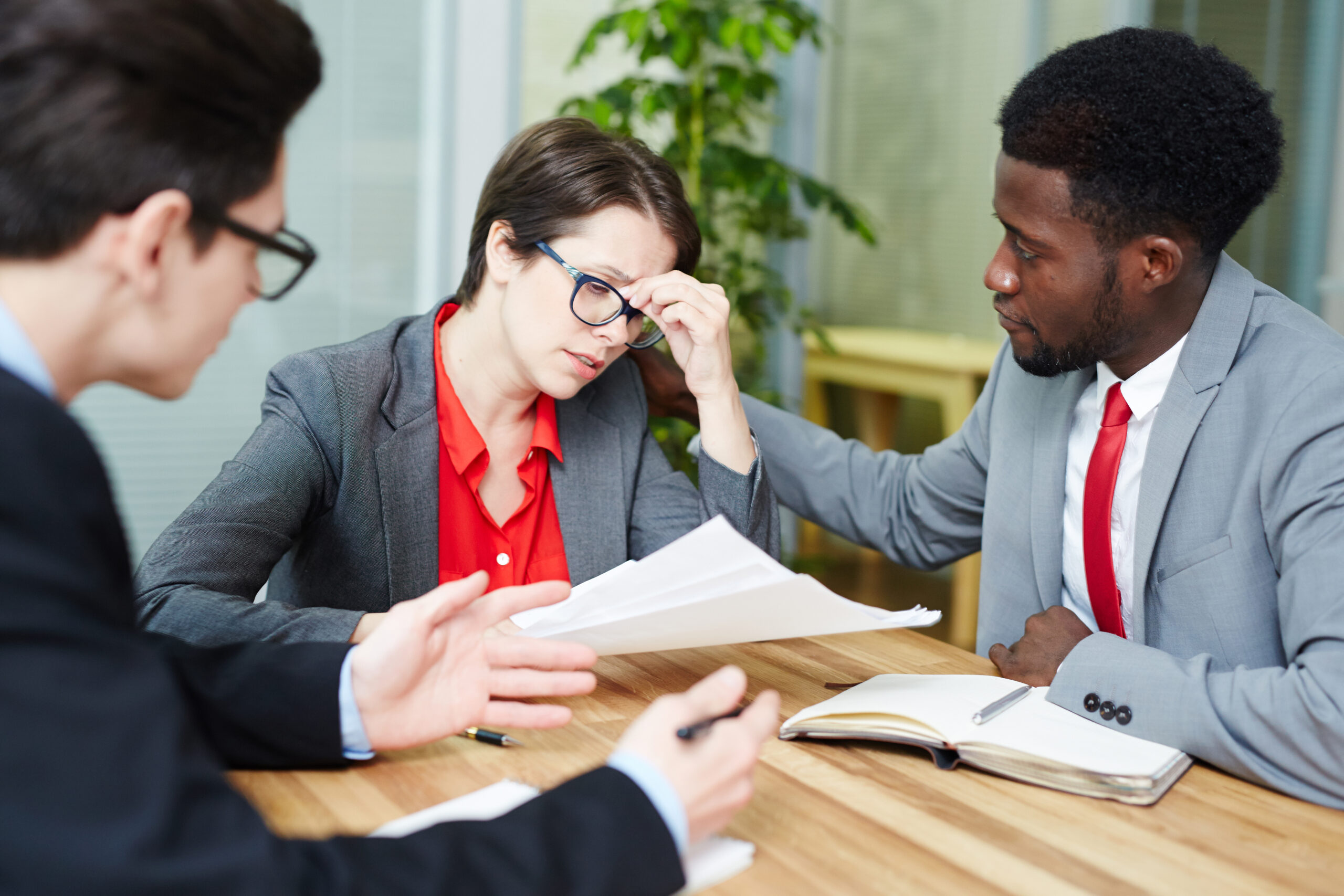 Stressed woman reviewing documents with lawyers, personal injury consultation.