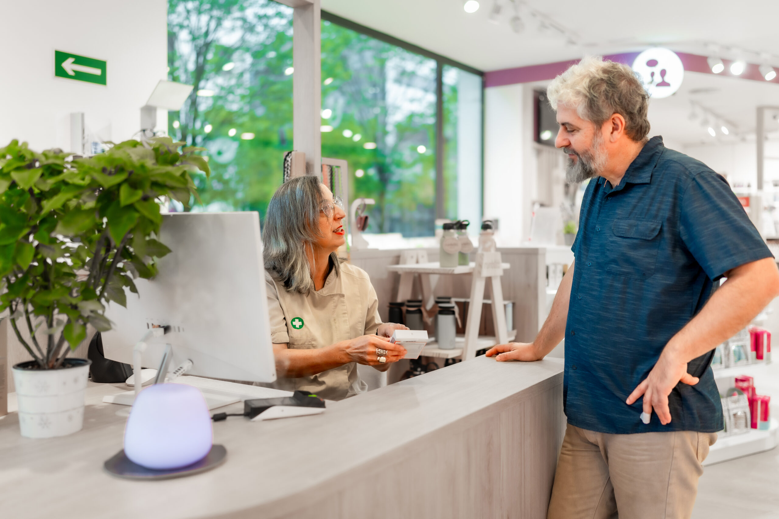 Pharmacist assisting customer in dispensary, considering dispensary selection factors.
