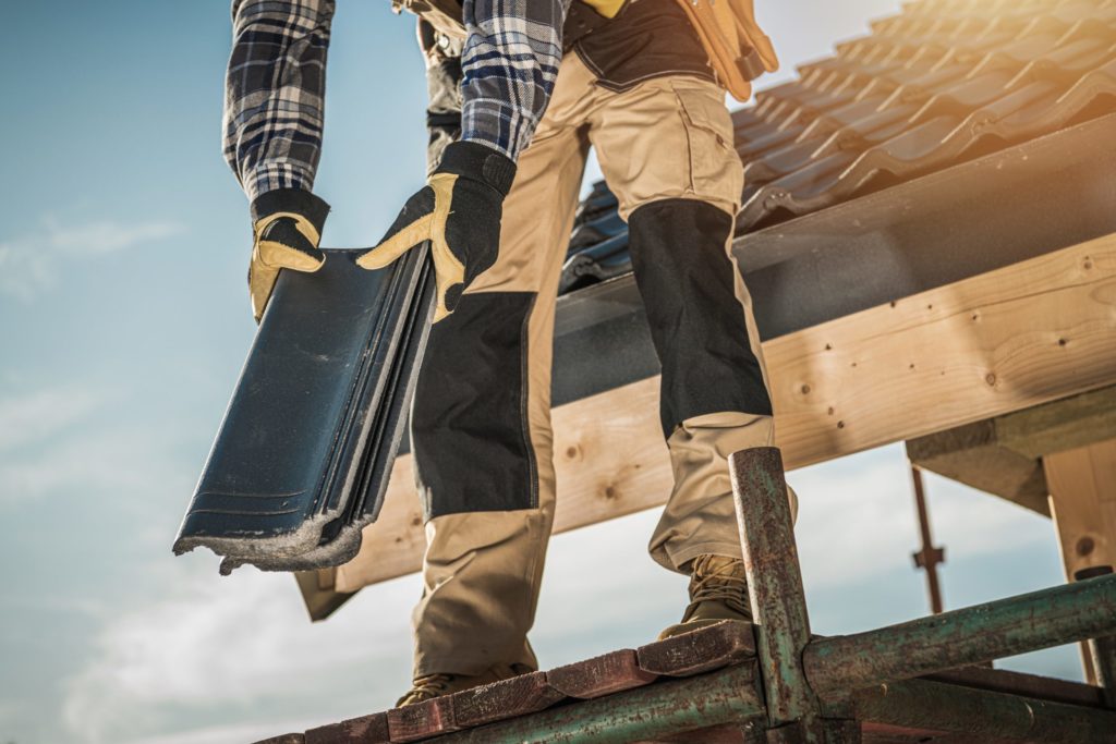 Construction Industry. Roofer with Ceramic Tiles in Hands. Roof Worker Closeup. House Rooftop Covering.